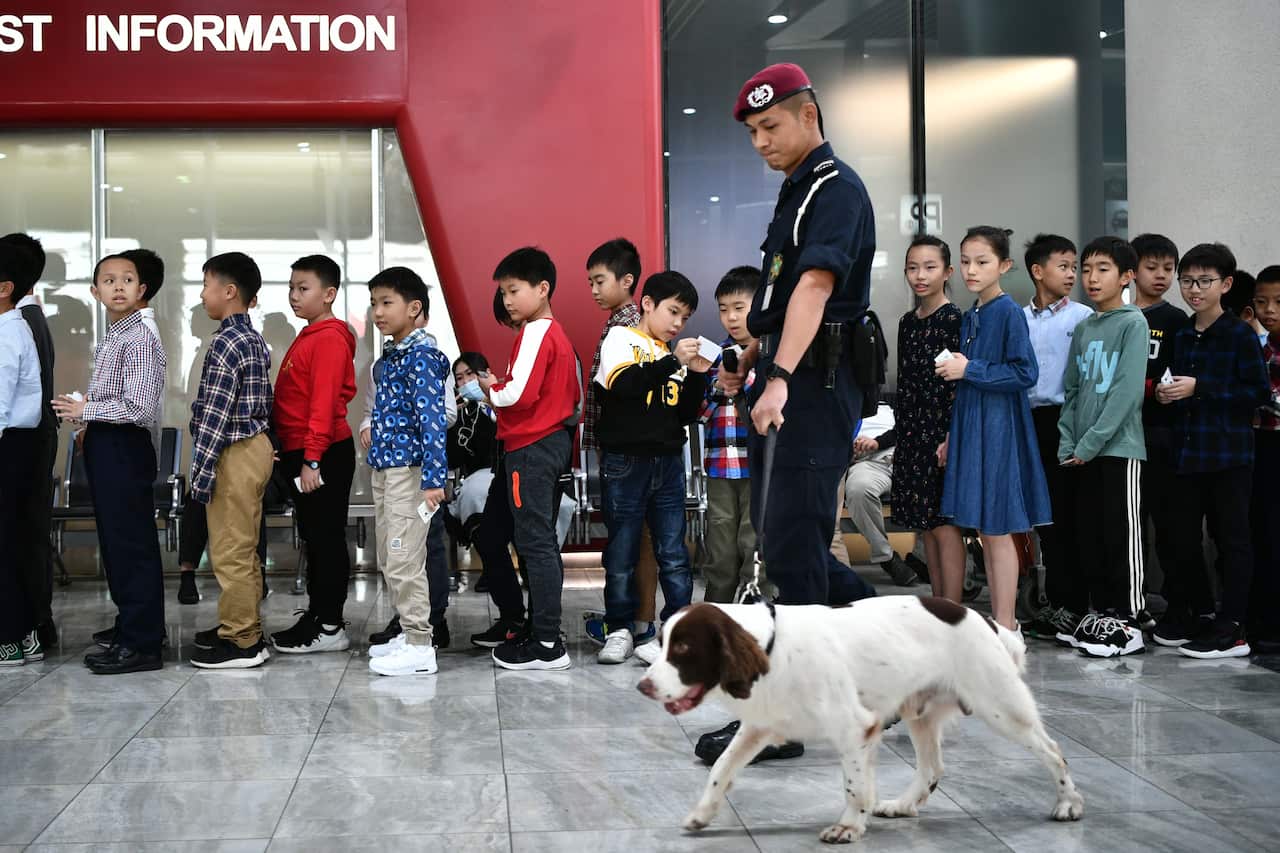 A police officer with a sniffer dog walks past children taking part in the welcome ceremony for China's President Xi Jinping.
