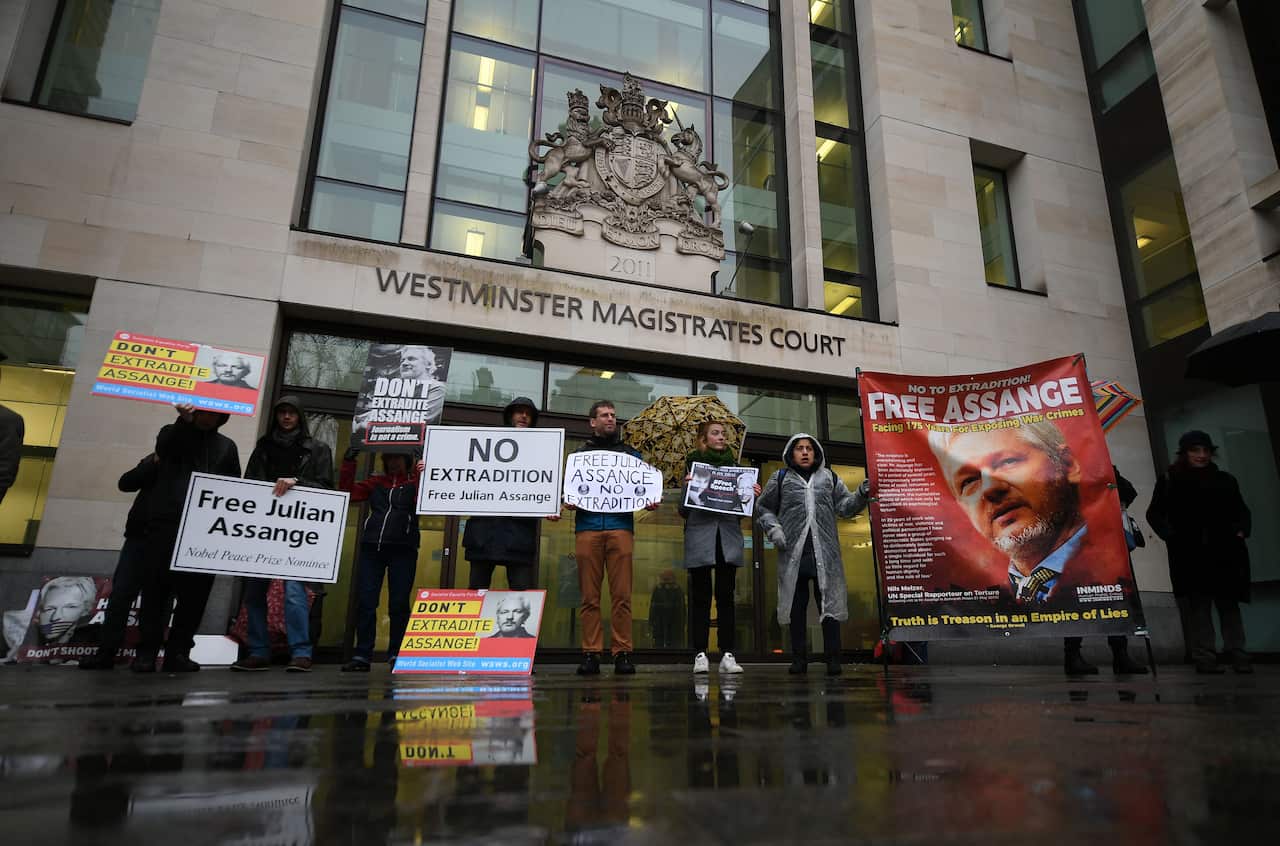 Supporters of WikiLeaks founder Julian Assange hold placards as they demonstrate outside the entrance to Westminster Magistrates Court.