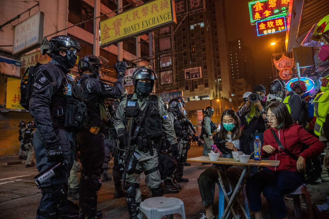 Riot police officers speak with customers of a street food store during tense demonstrations.