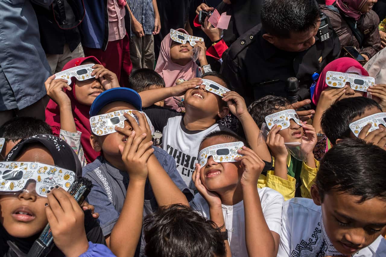 Children watch the moon move in front of the sun in a rare "ring of fire" solar eclipse in Surabaya on December 26, 2019. (Photo by JUNI KRISWANTO / AFP) (Photo by JUNI KRISWANTO/AFP via Getty Images)