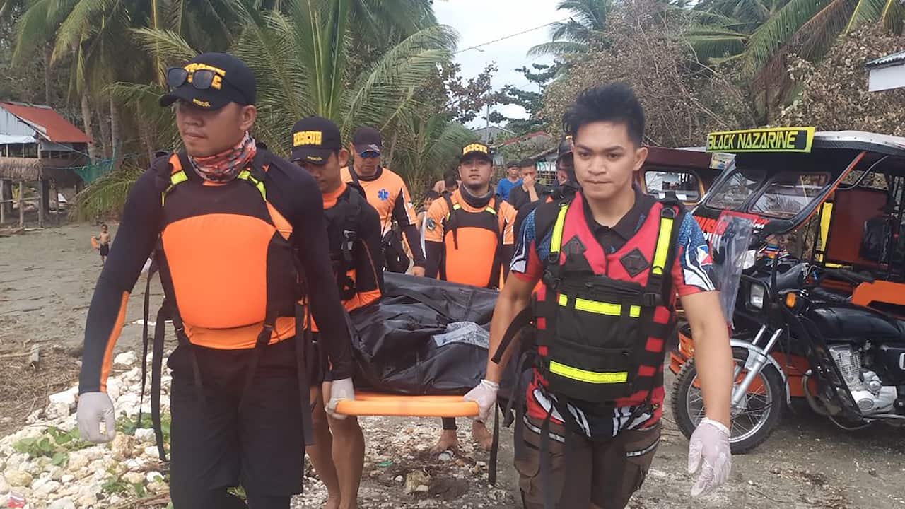 Rescuers carry a body believed to be one of several fishermen who went missing at the height of Typhoon Phanfone.