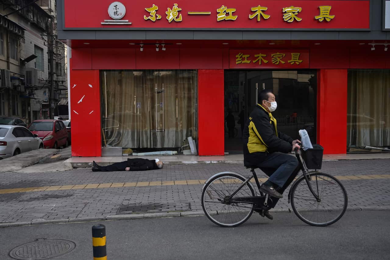 A man cycles past after an elderly man collapsed and died in a Wuhan street.