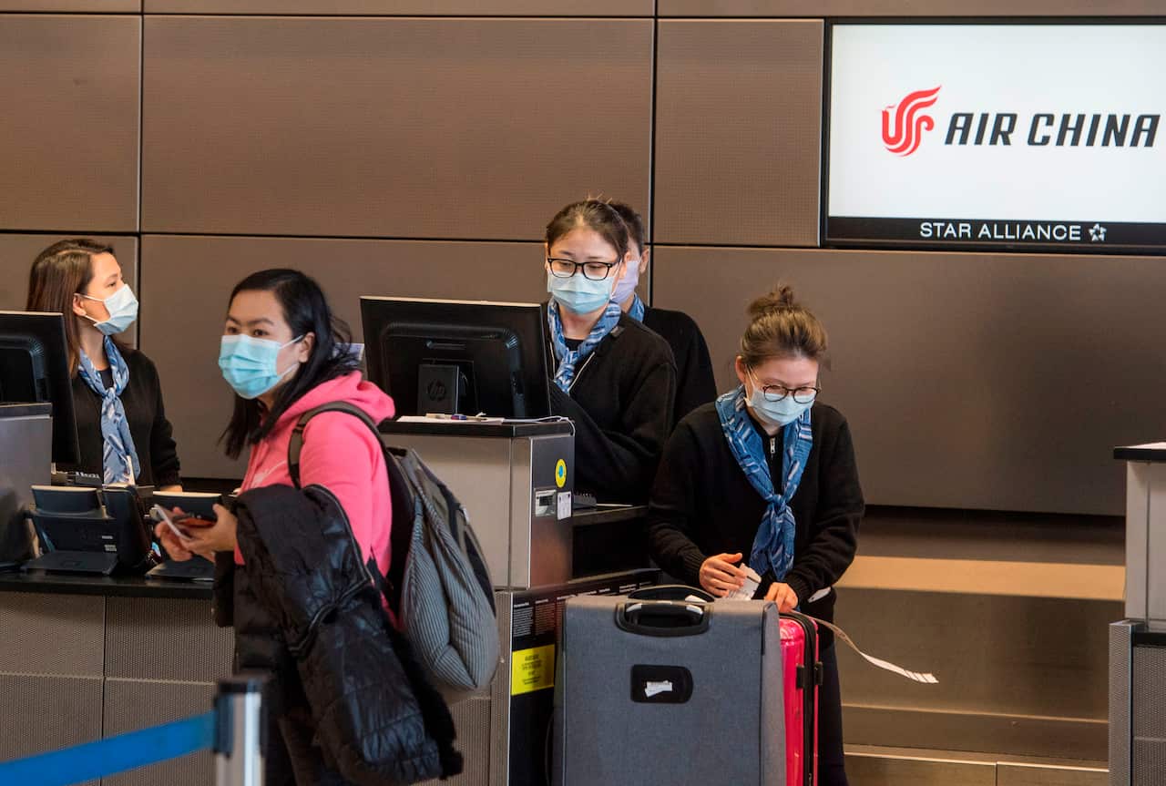 Chinese citizens wear face masks as they check in to their Air China flight to Beijing, at Los Angeles International Airport.