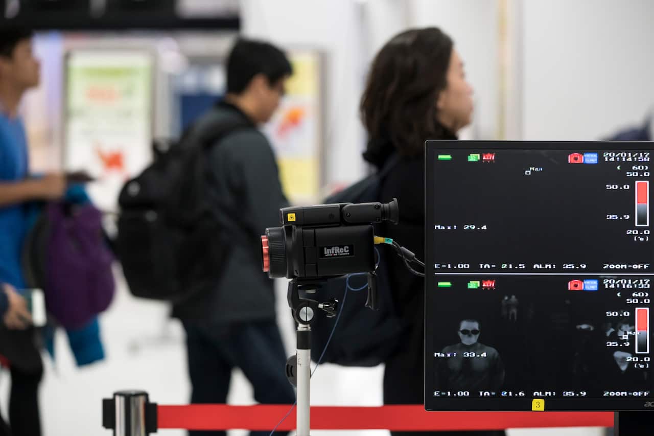 A health worker monitors a thermal scanner as passengers arrive at Japan's Narita airport.