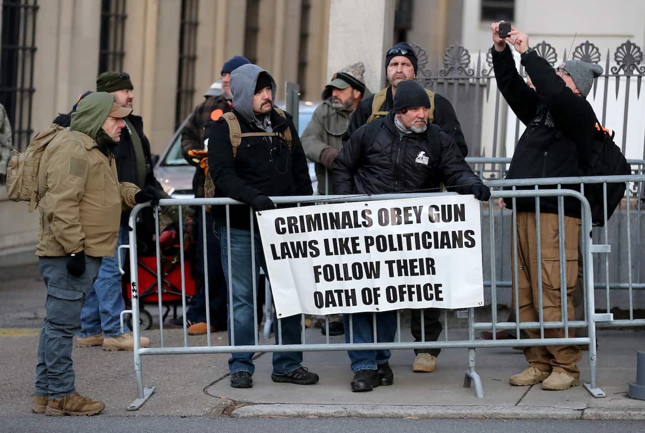 Attendees carry signs expressing their views on gun control.
