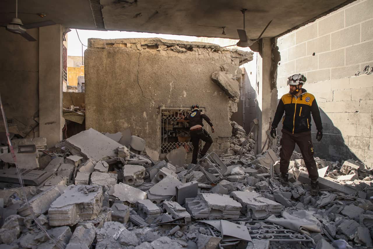 Members of the Syrian Civil Defence inspect debris and rubble as they search for survivors at a destroyed hospital in the town of Darret Ezza.