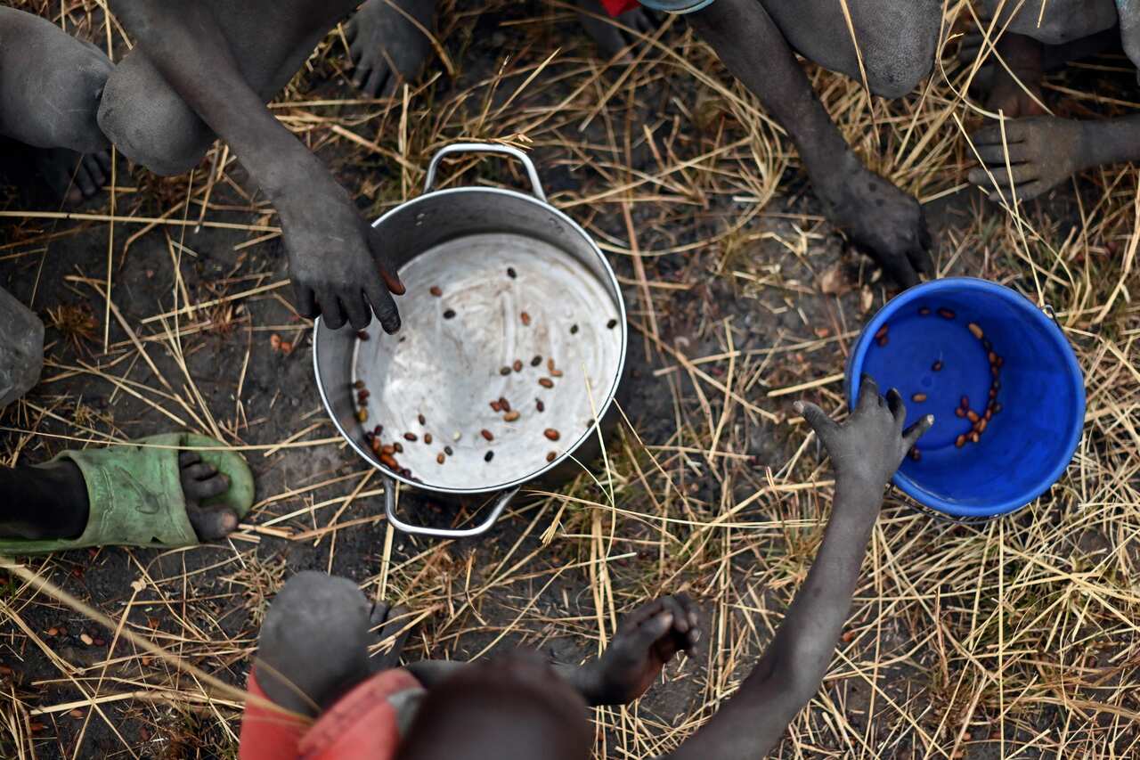 Children collect grain spilt from food aid bags after being dropped from a plane. 