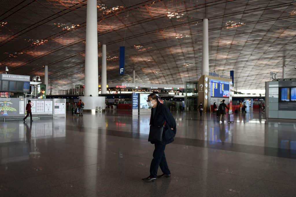 A man wears a face mask as a preventive measure against the COVID-19 coronavirus as he walks through an almost empty Beijing Capital Airport
