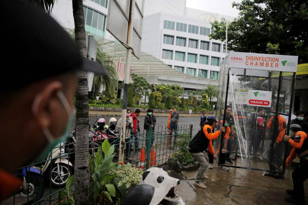 Indonesia people reacts as she is sprayed with disinfectant inside a makeshift sterilisation chamber