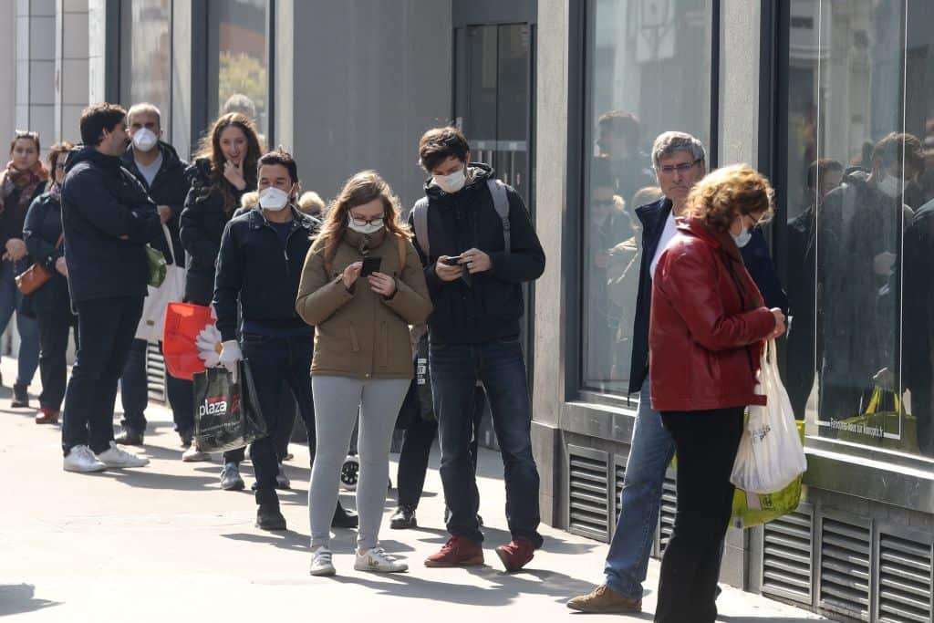 People wait in line at the entrance of a supermarket in Paris