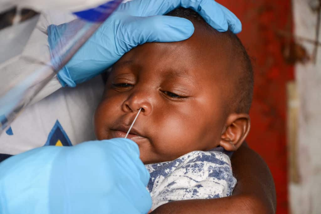 A health worker performs a nose swab test on a minor during