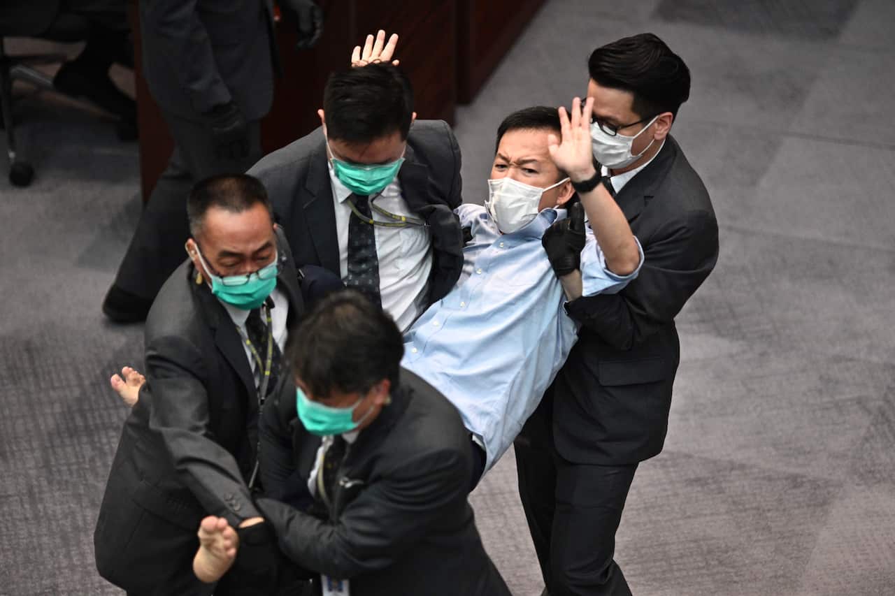 Pro-democracy politician Raymond Chan (C) is carried away by security following scuffles at the Legislative Council in Hong Kong on 8 May.