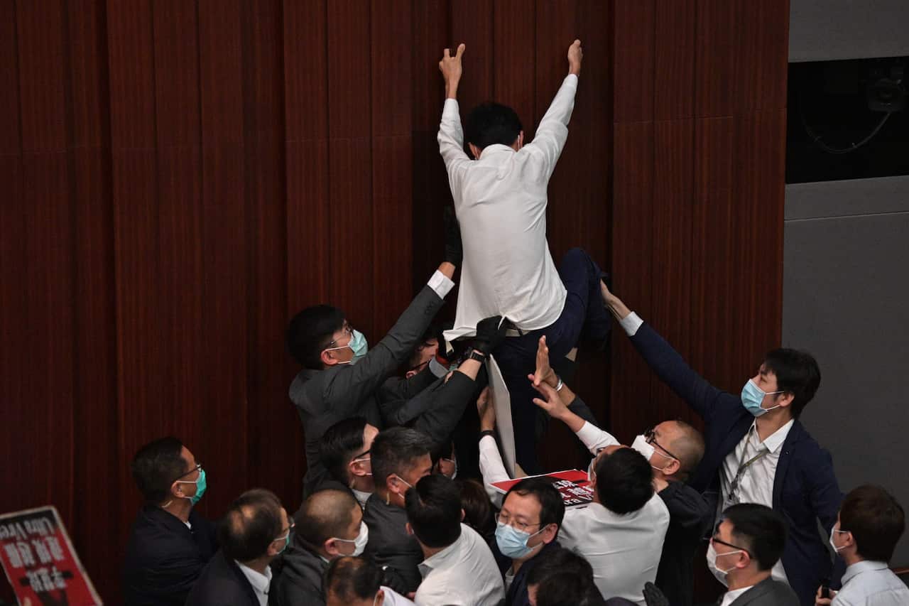 Pro-democracy politician Eddie Chu Hoi-dick tries to climb a wall in protest as security try to restrain at a Legislative Council meeting in Hong Kong on May 8.