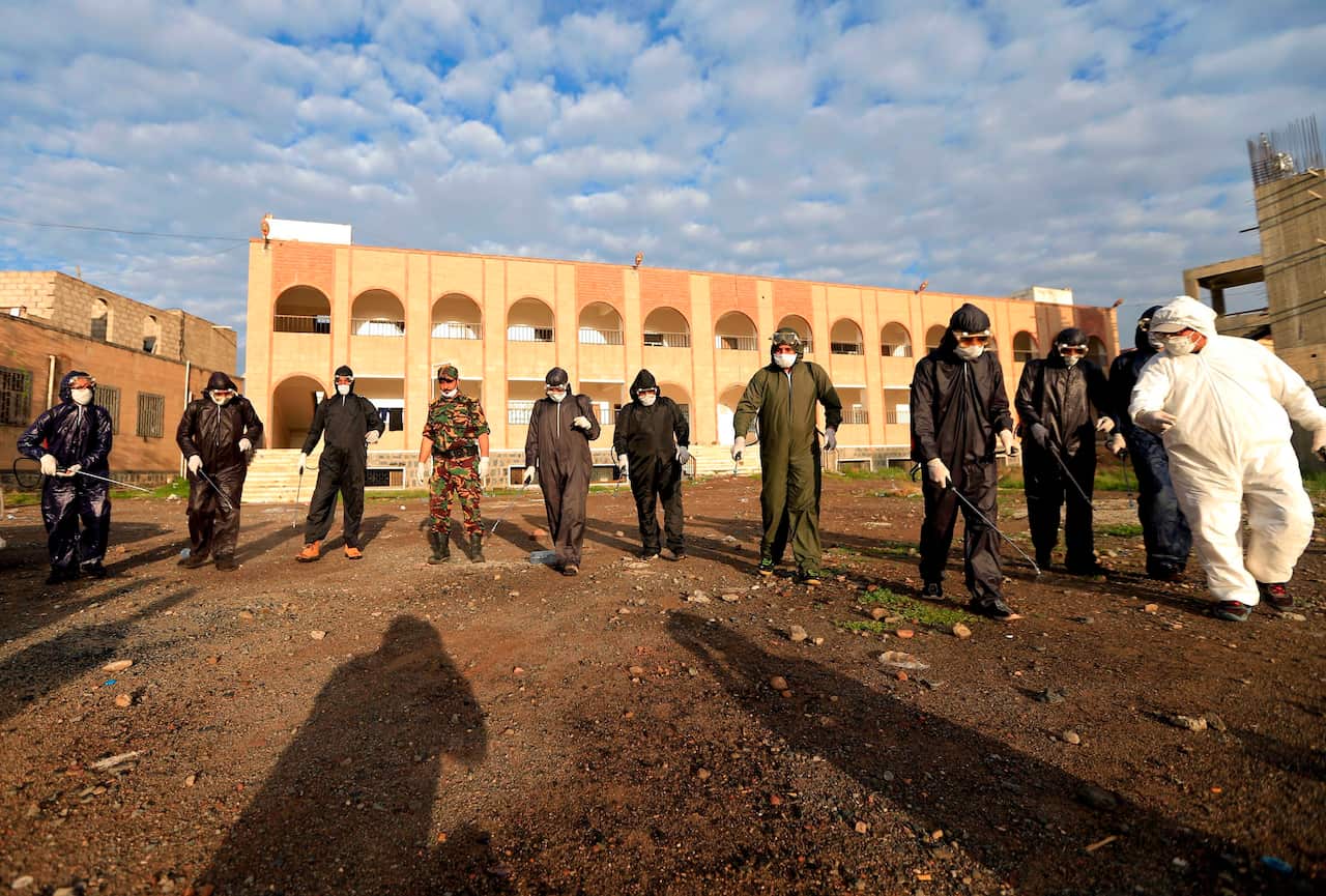Yemeni security personnel disinfect an area outside a security headquarters in the Huthi-rebel-held capital Sanaa.