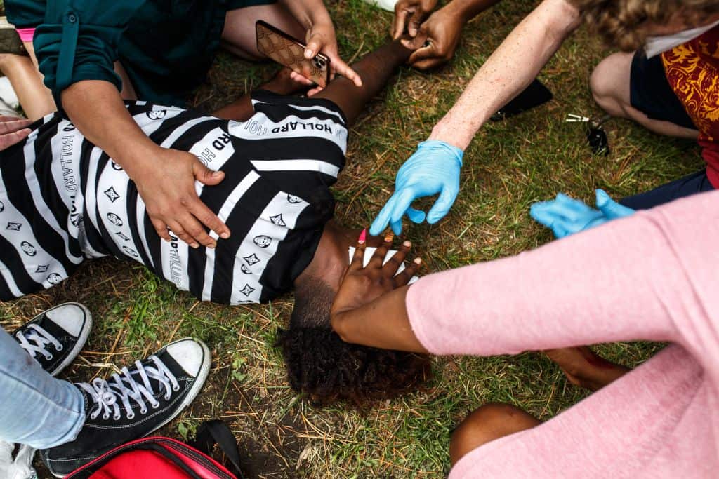 An injured young Somali-American man is helped by others as protesters clash with the police
