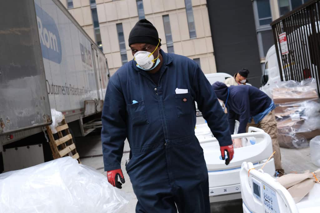 Workers prepare dozens of extra medical beds as they are delivered to Mount Sinai Hospital, New York, 31 March, 2020.
