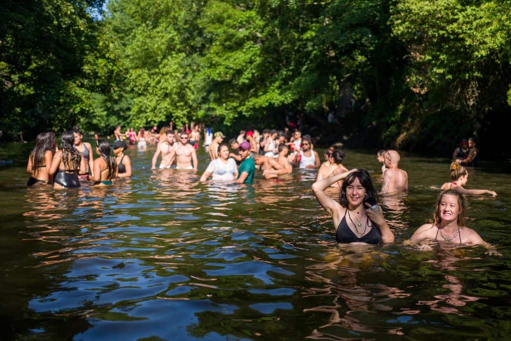 Sun-seekers cool off in the water and sunbathe on the riverbank at Hackney Marshes in east London.