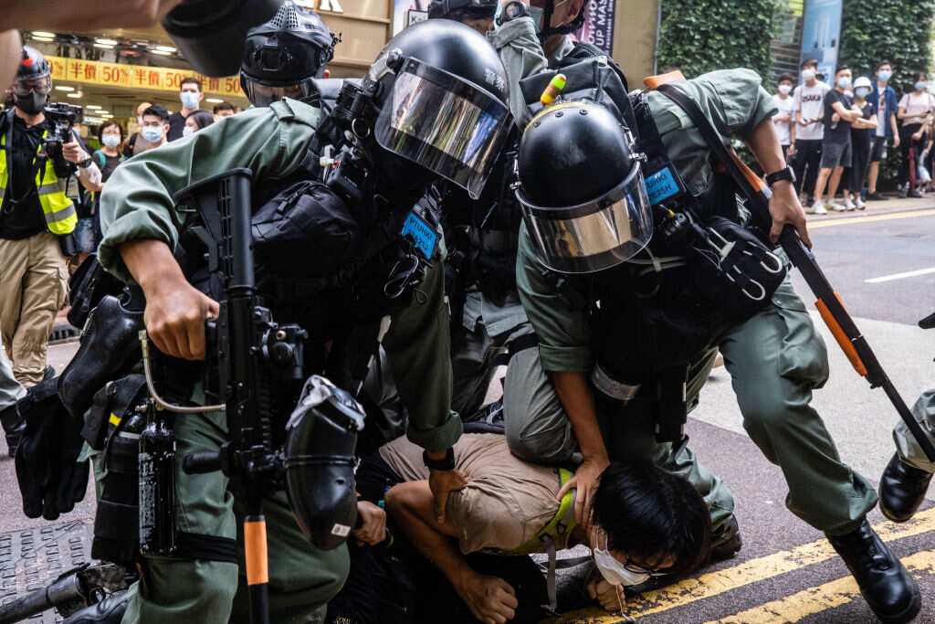 Riot police officers pinning down a protester during the