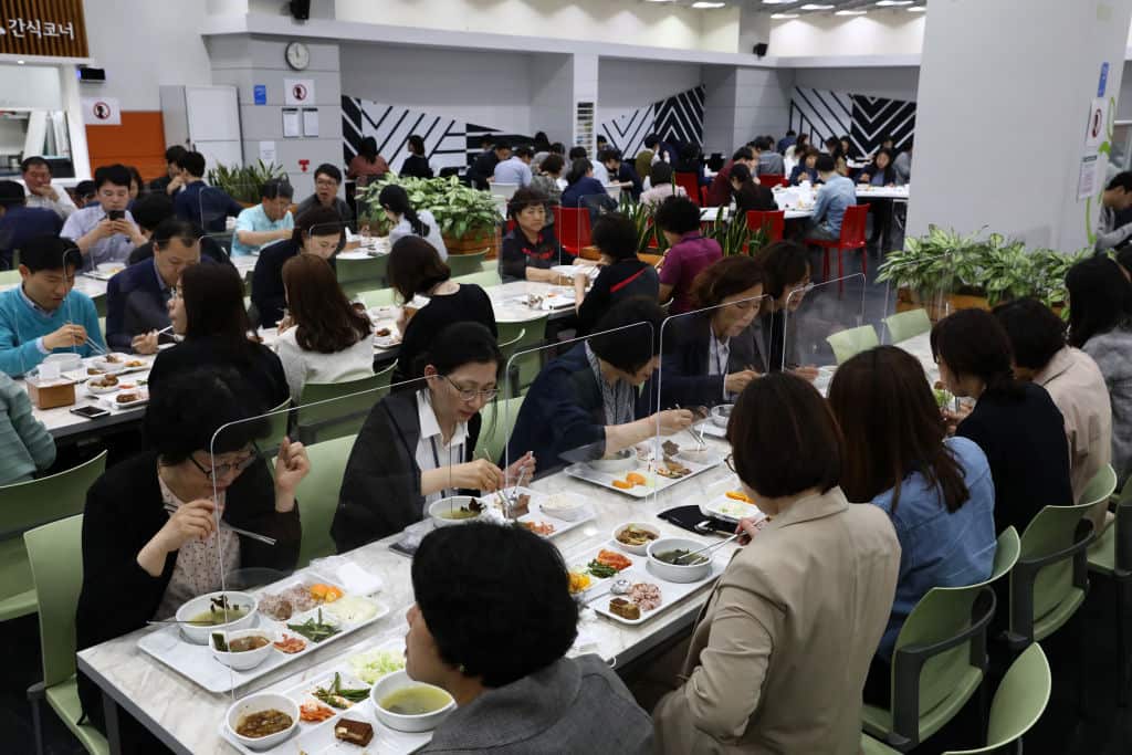 People eat lunch behind protective plastic barriers in Seoul
