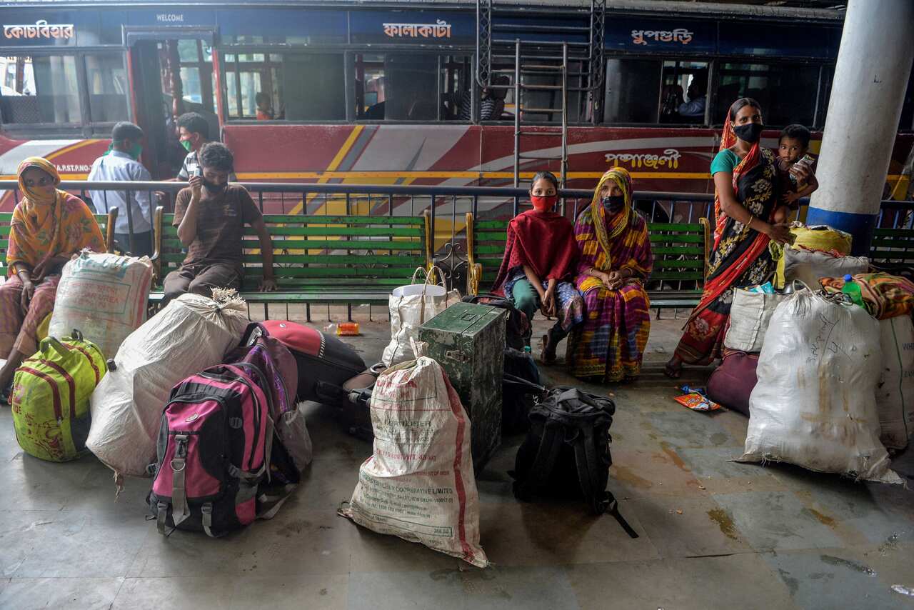 Migrant labourers and their families travelling from Kerala to Assam states wait, stranded, at a bus station after the new lockdown came into force.