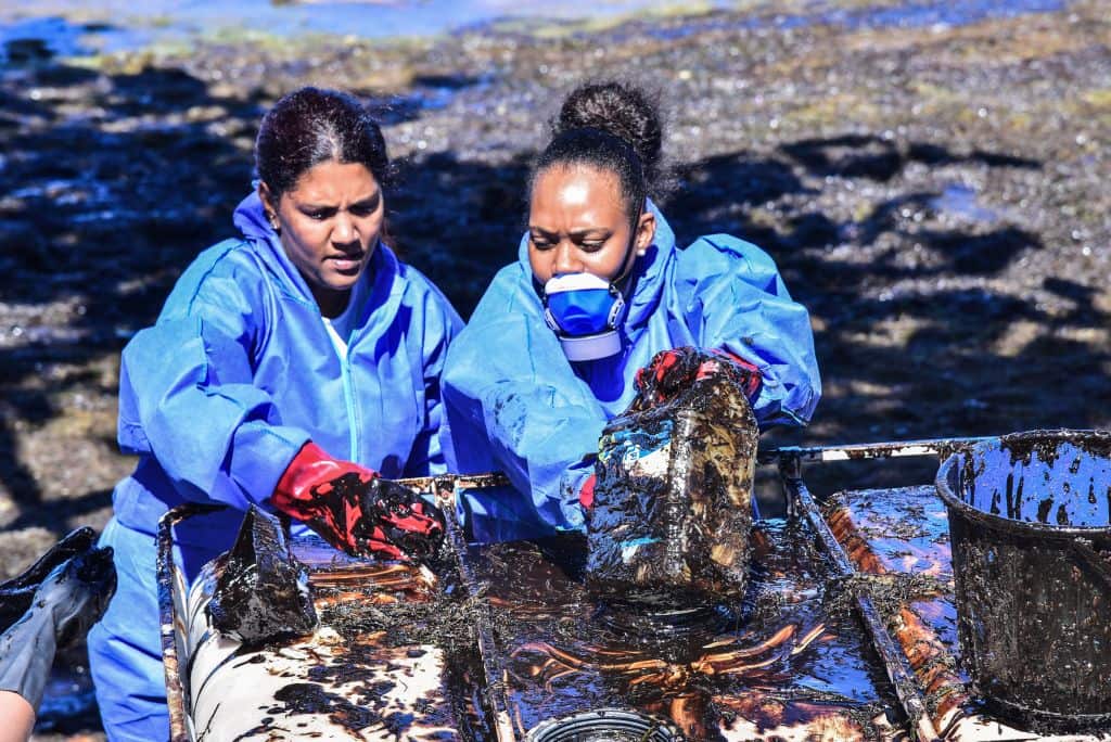 Volunteers collect leaked oil at the beach in Mahebourg