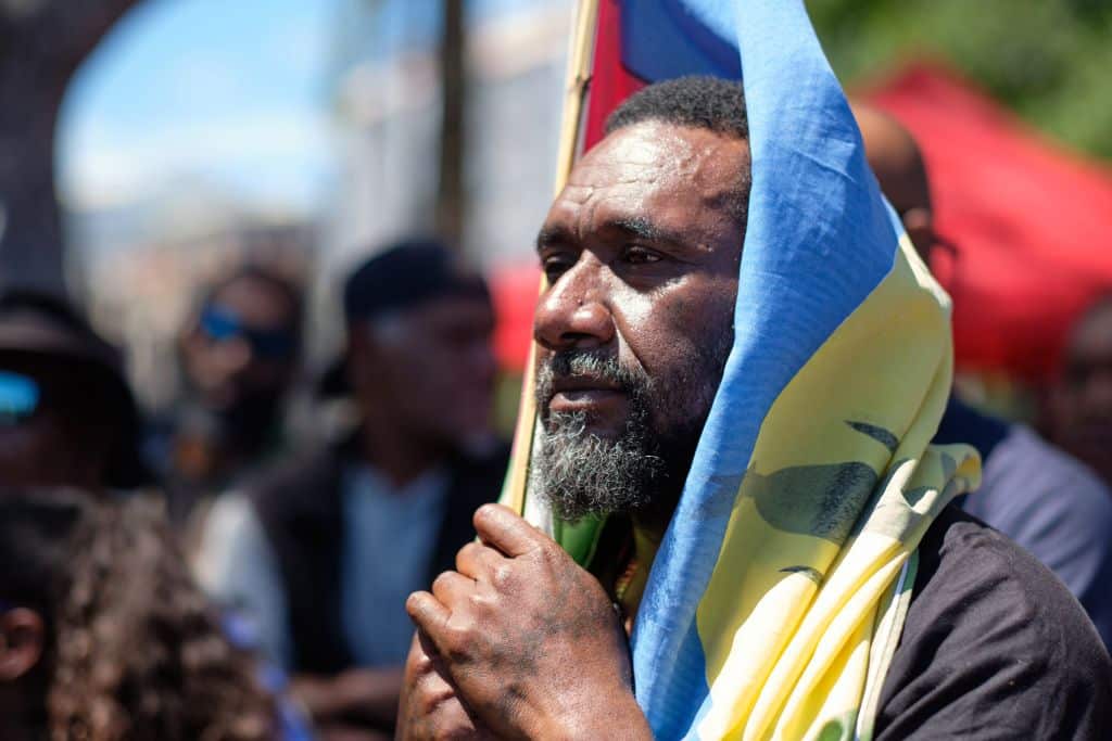 A pro-independence sympathiser with a flag of the Socialist Kanak National Liberation Front (FLNKS).