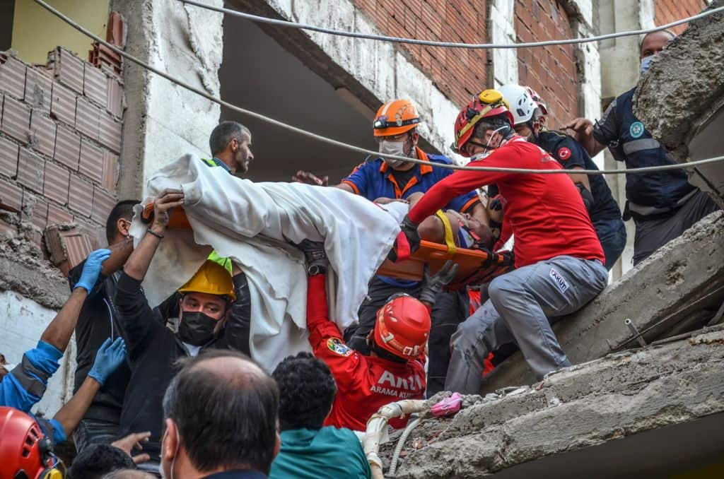 Rescuers and local volunteers carry a wounded victim on a stretcher from a collapsed building after a powerful earthquake struck Turkey's western coast and parts of Greece.