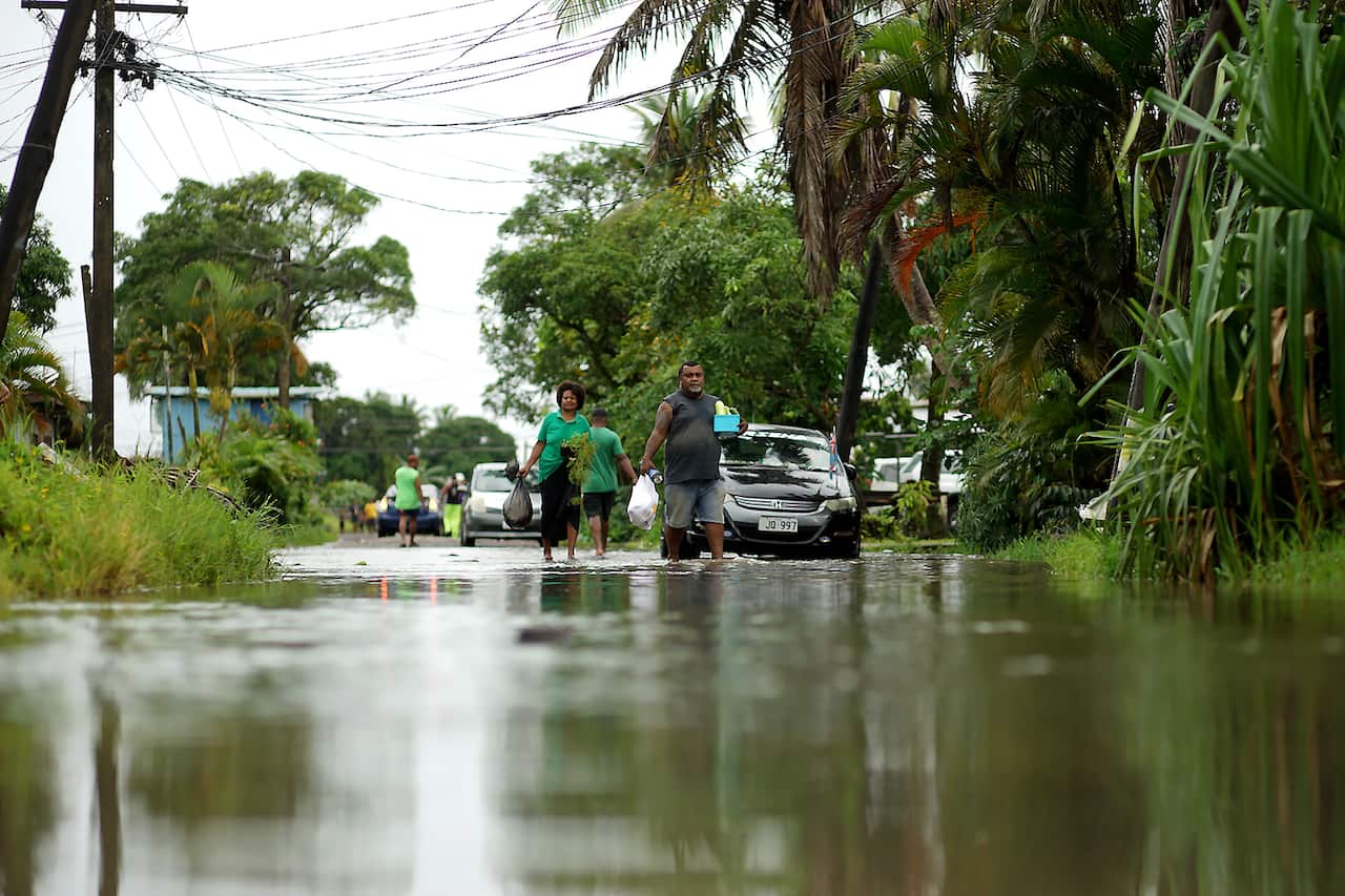 Residents wade through the flooded streets in Fiji's capital city of Suva on December 16, 2020, ahead of super Cyclone Yasa. 