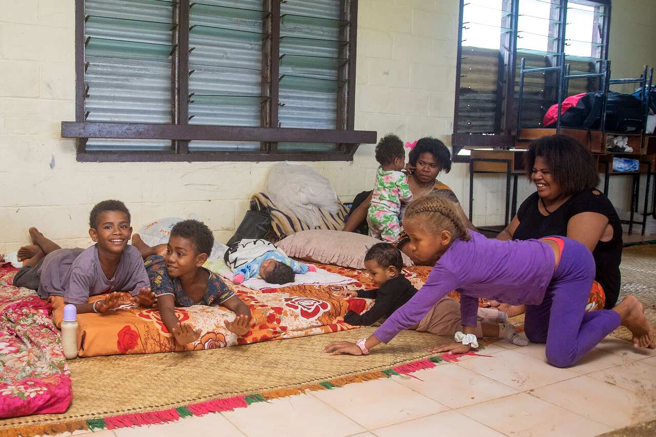A Fijian family takes refuge in a temporary shelter from the strong damaging winds in Suva.