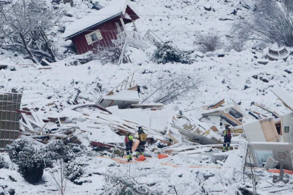 Rescue workers are seen in the crater left behind by a landslide in the town of Ask, Norway.