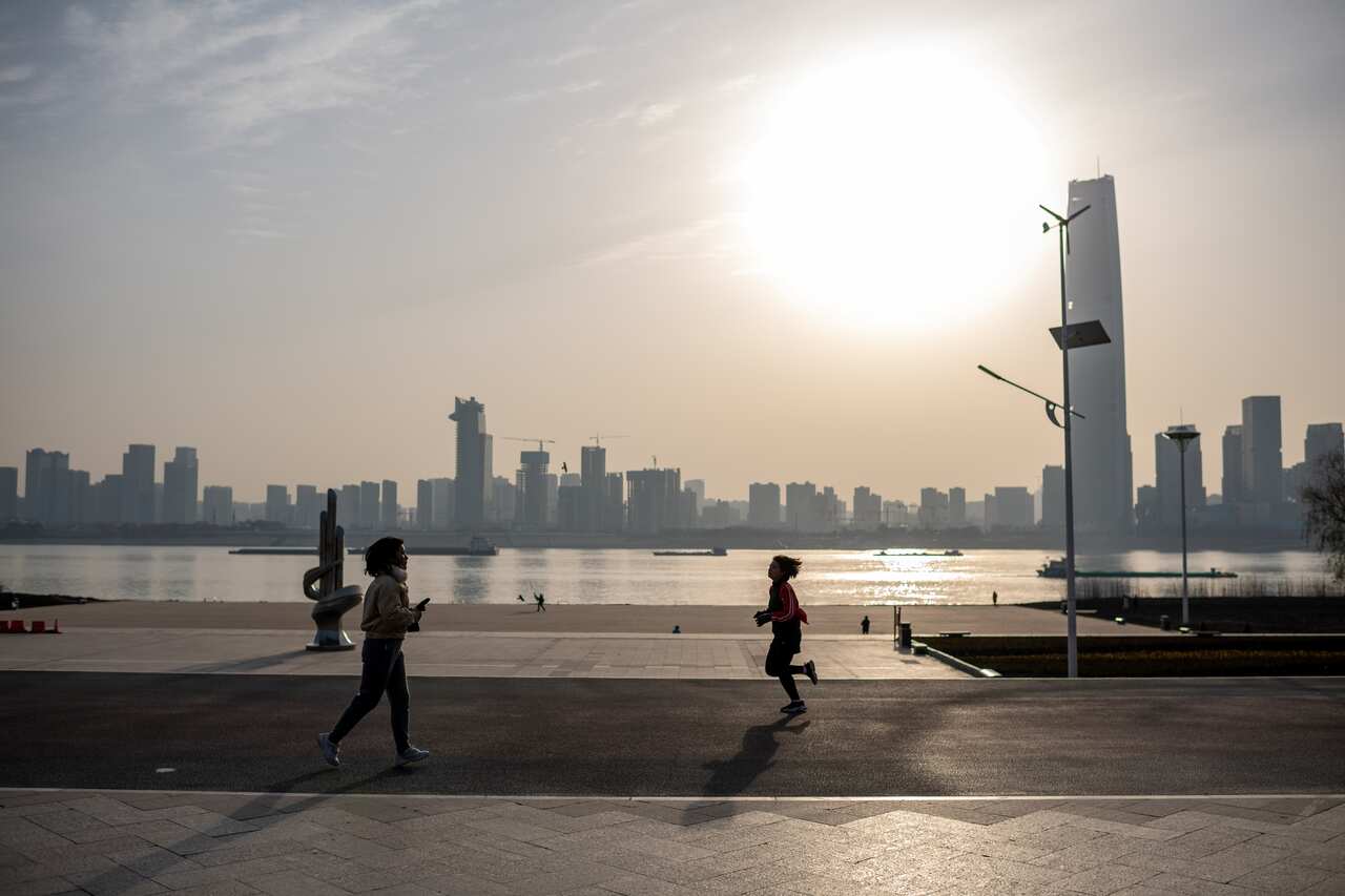 People run along the banks of the Yangtze River in Wuhan on 11 January, as the city marks the first anniversary of China confirming its first COVID-19 death.