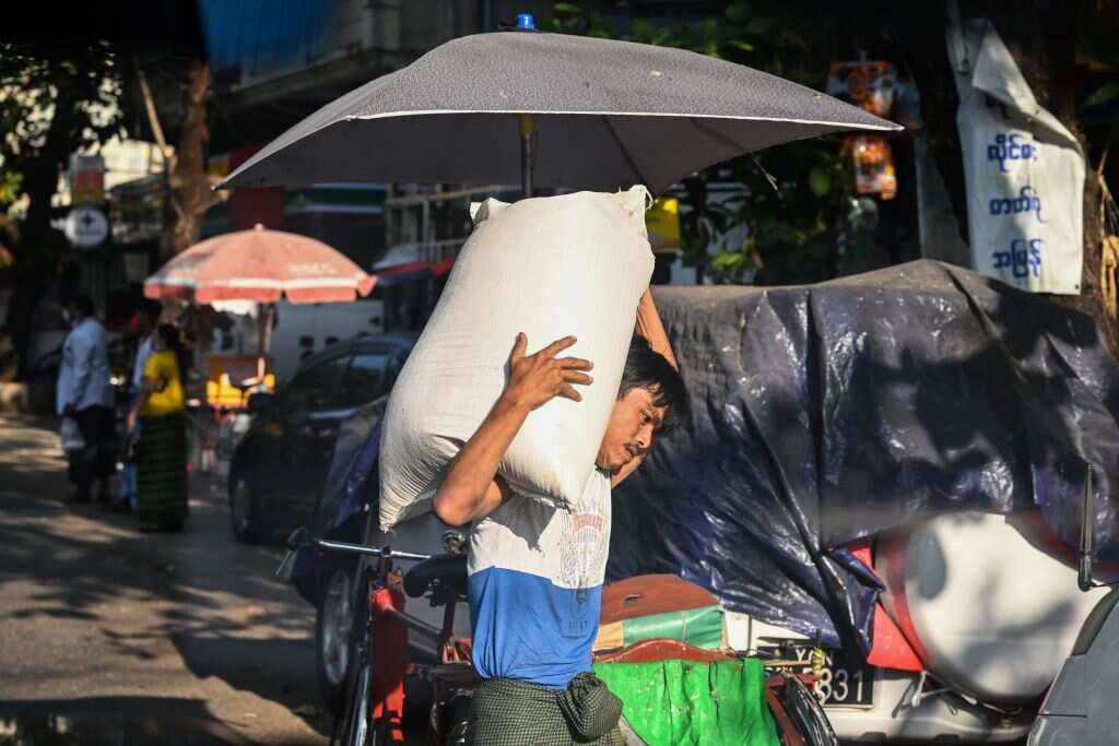 A man carries a sack of rice from market in Yangon on February 1, 2021, as Myanmar's military detained the country's de facto leader Aung San Suu Kyi and the country's president in a coup.