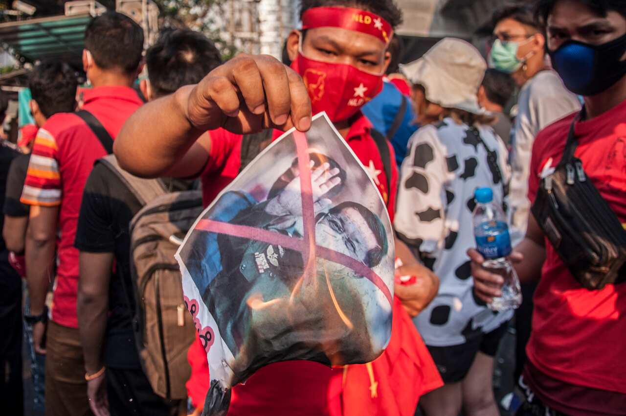 A National League for Democracy (NLD) supporter holds a burning portrait of Myanmar's army chief Min Aung Hlaing during a demonstration in Bangkok on 2 January.