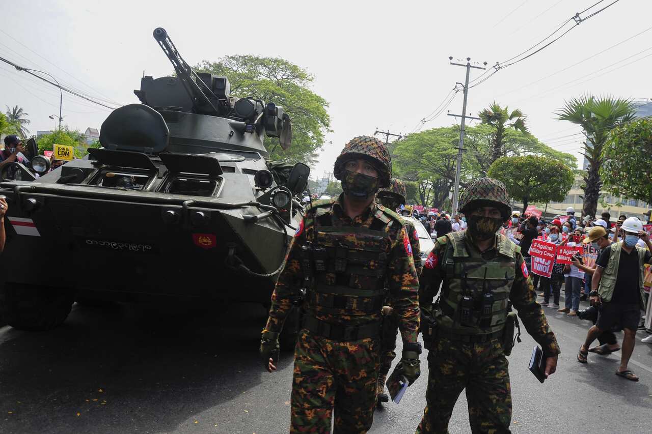 Soldiers walk near an armoured personnel carrier while people protest against the military coup, outside the Central Bank of Myanmar, in Yangon.