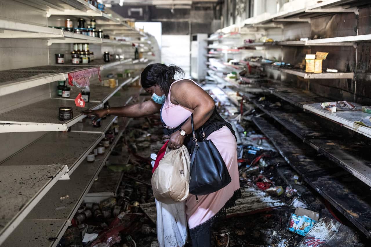 A woman collects food and drinks from a burnt down and looted Auchan supermarket in the up-market area of Almadies in Dakar on 6 March, 2021.
