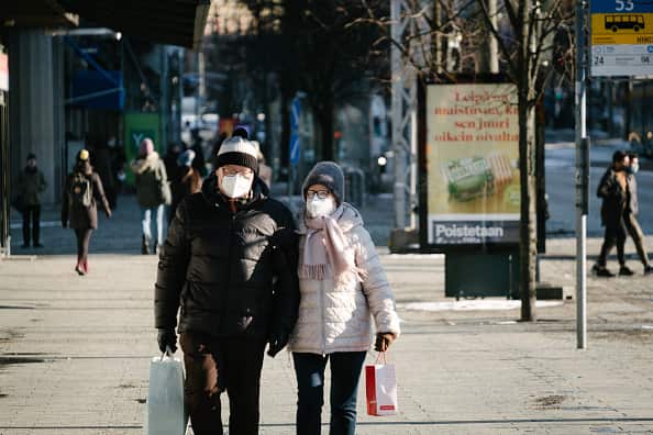 Man and woman wearing masks as they walk along street in Helsinki, Finland.
