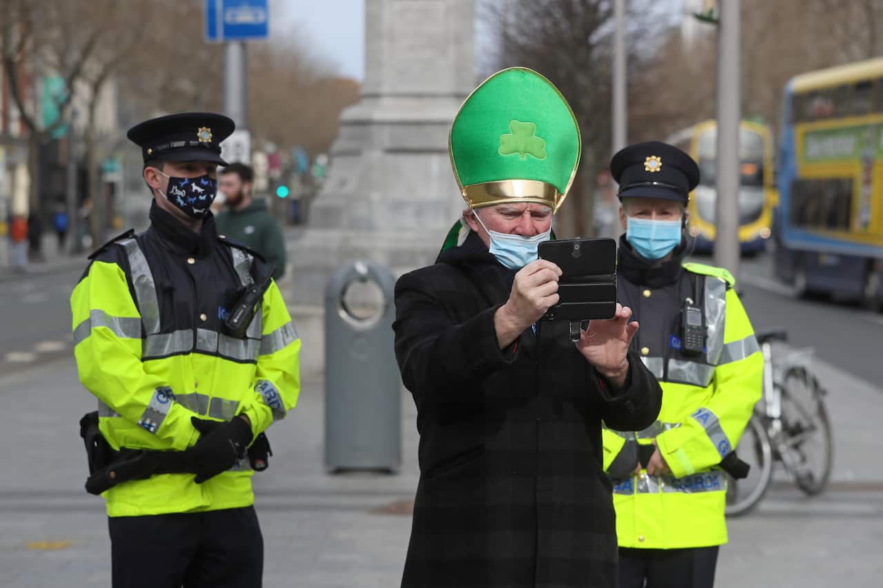A man dressed up to celebrate St Patrick's day takes selfie with members of An Garda in Dublin city centre 17 March 2021.