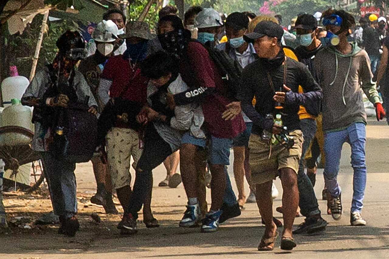 Protesters carry an injured protester during a demonstration against the military coup.