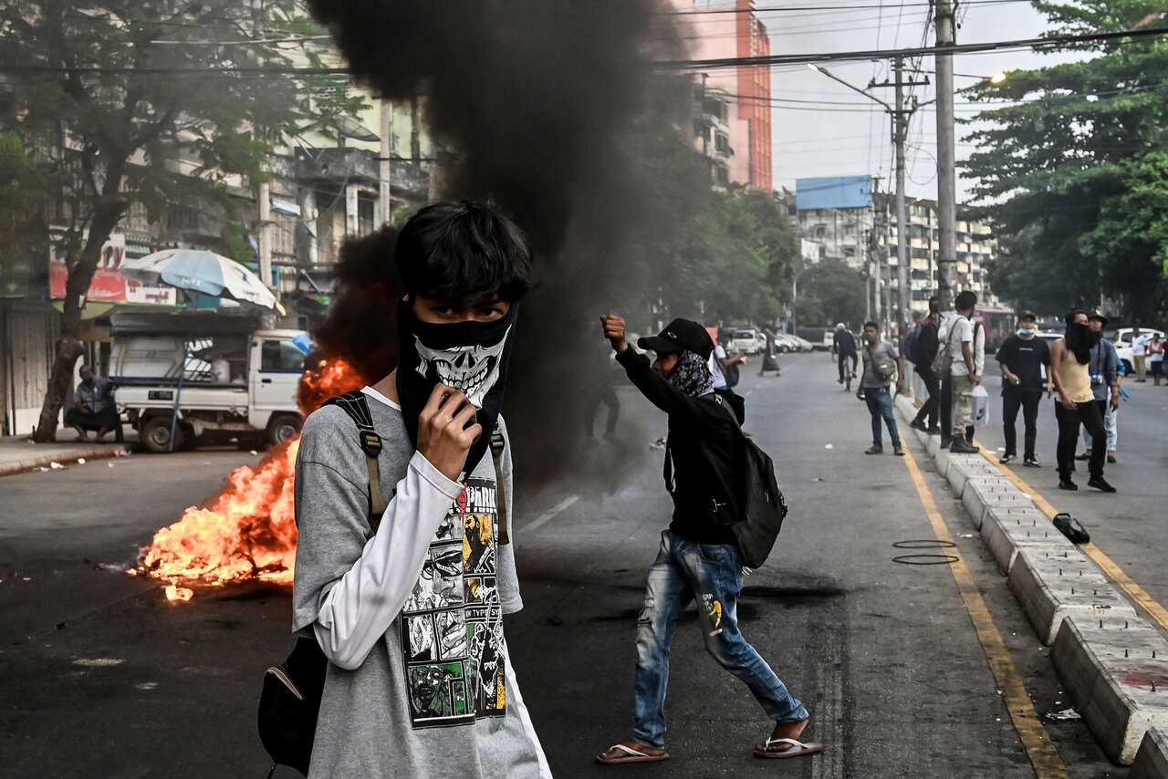 Protesters stand near a burning barricade during a protest.