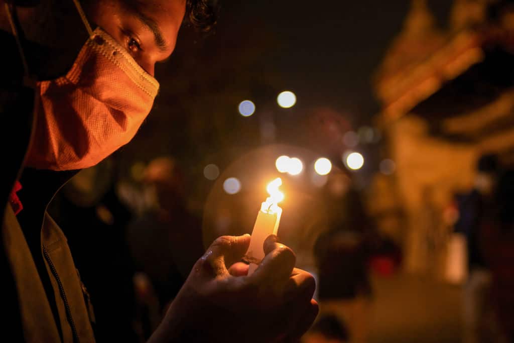 A protester holding a burning candle attends a candlelight vigil for those who died in protests during Myanmar's military coup.