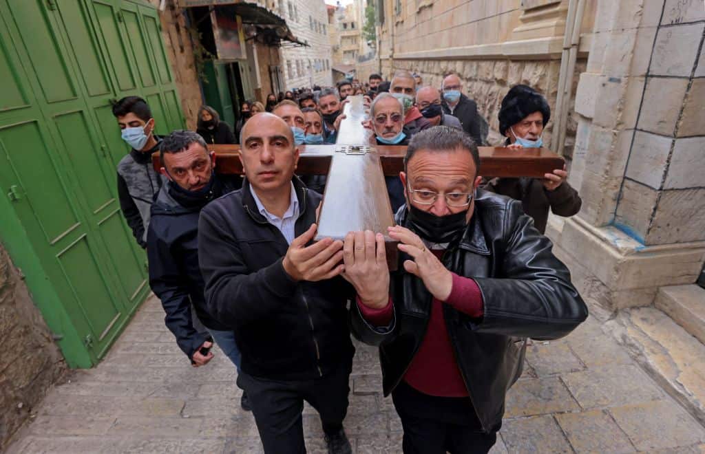 Christian worshippers carry a wooden cross along the Via Dolorosa in Jerusalem's Old City during the Good Friday procession on 2 April, 2021. 
