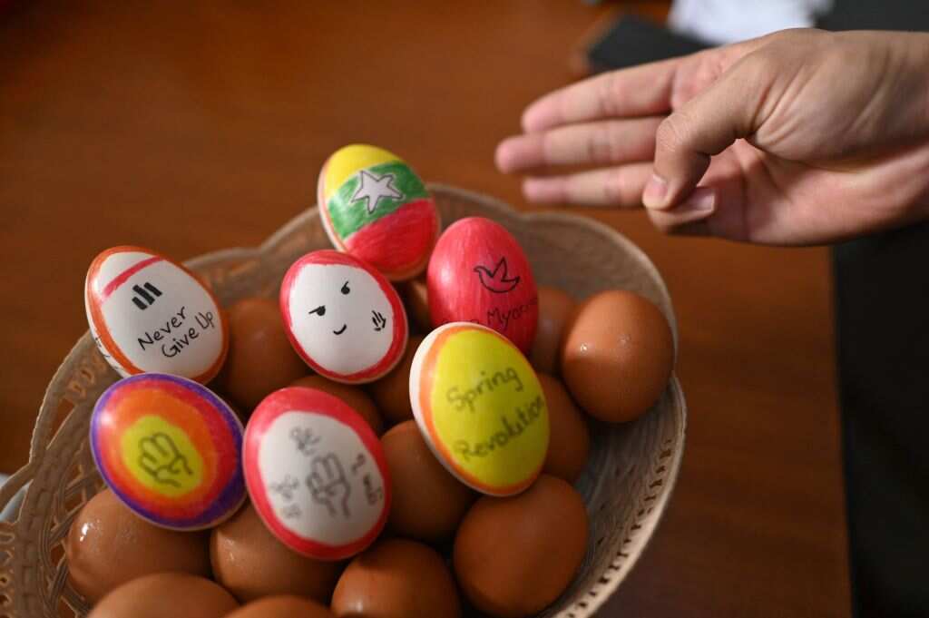A person makes the three-finger salute beside a bowl of eggs, decorated with messages in support of protesters 