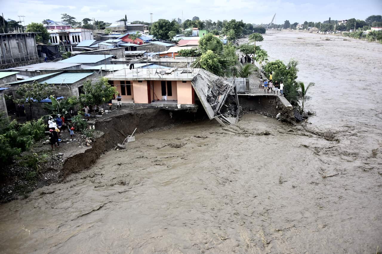 Residents stand along the water's edge by damaged homes after heavy rains and strong winds lashed Timor-Leste's capital Dili on 4 April.