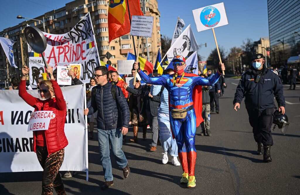 Protesters, including a man wearing a Superman suit, hold banners and placards at an anti COVID-19 vaccination rally in Romania.