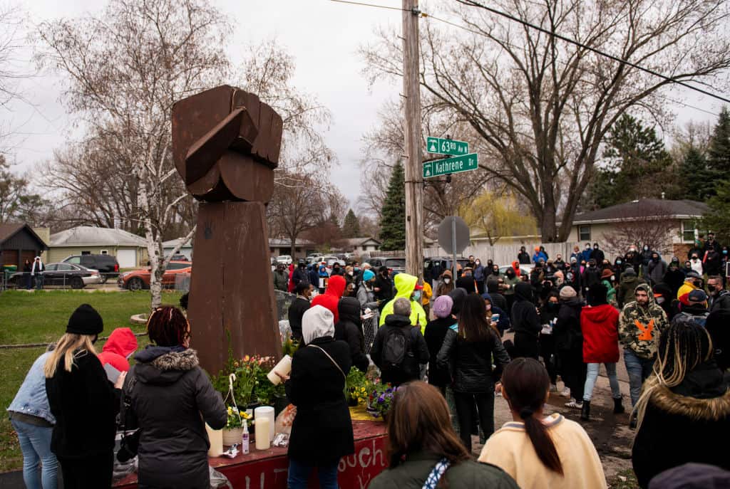 People gather around a sculpture of a raised fist during a vigil for Daunte Wright 