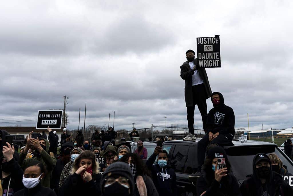 People gather holding signs and flags before curfew to protest the death of Daunte Wright