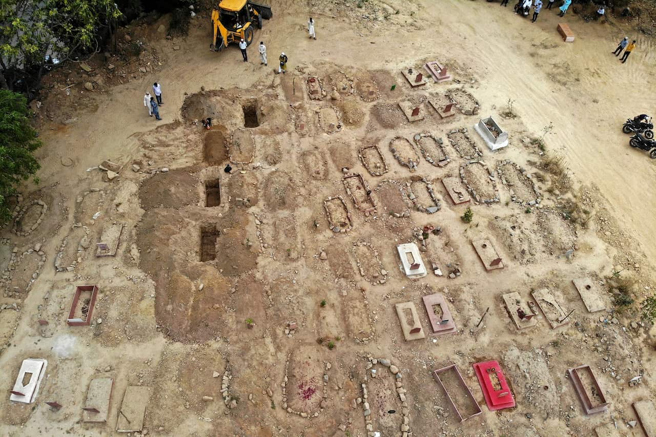 In this aerial picture taken on 16 April, 2021, relatives and friends gather to bury the dead bodies of coronavirus victims at a graveyard in New Delhi. 