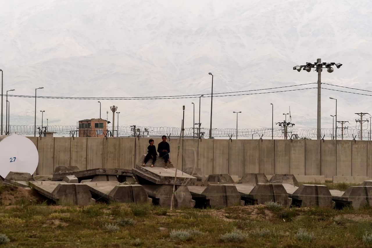 Children sit outside a US military base in Bagram, some 50 km north of Kabul on 29 April, 2021.