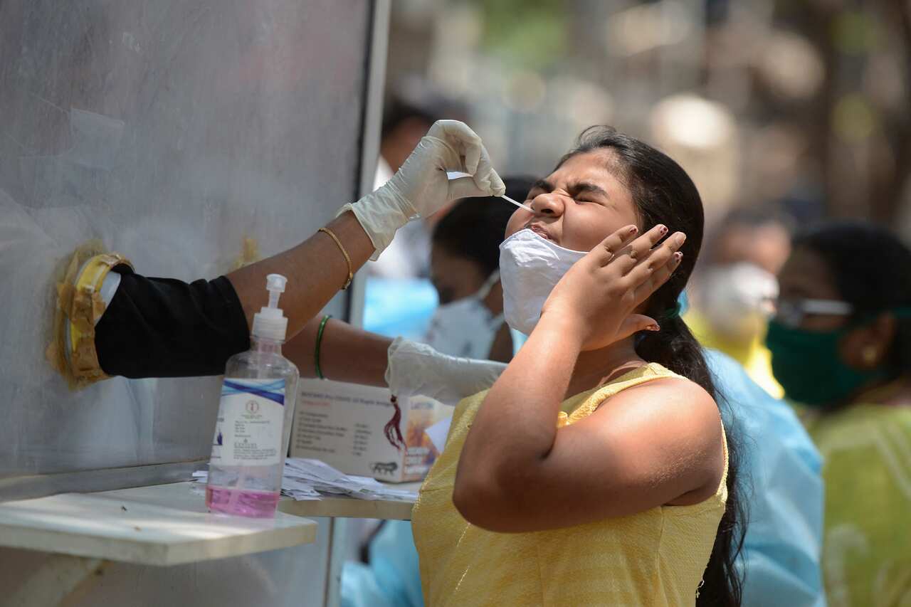 A health worker collects a nasal swab sample from a girl to test for the Covid-19 coronavirus at primary health centre, in Hyderabad on May 3, 2021. (Photo by NOAH SEELAM / AFP) (Photo by NOAH SEELAM/AFP via Getty Images)