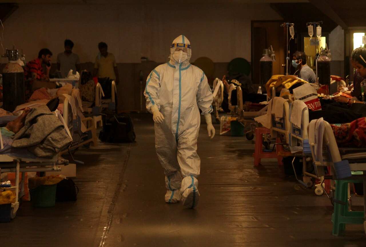 A health worker takes care of patients inside a banquet hall, temporarily converted into a quarantine facility for COVID-19 patients, in New Delhi on 4 May.